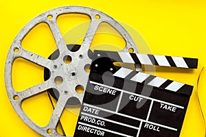 Filmmaker profession with clapperboard and video tape on yellow background top view