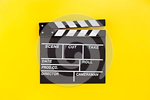 Filmmaker profession. Clapperboard on yellow background top view copyspace