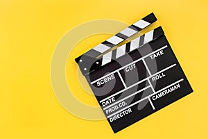 Filmmaker profession. Clapperboard on yellow background top view copyspace