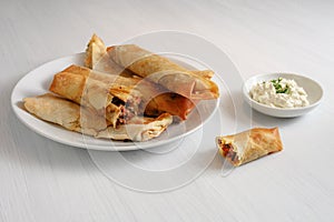 Filo or yufka dough rolls stuffed with a spicy meat filling and cheese curd on a white painted table, copy space