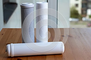 Filter cartridges for drinking water purification for on a wooden table against a blurred background. Water filtration RO