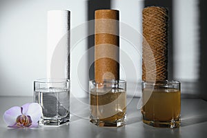 Filter system for water treatment with glasses of clean and dirty water on bright background