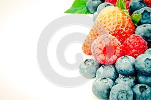 Filtered image studio shot pile of organic strawberries, blueberries and raspberries collection isolated