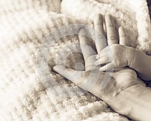 Filtered image of tiny baby hand in her mother palm for love and protection concept