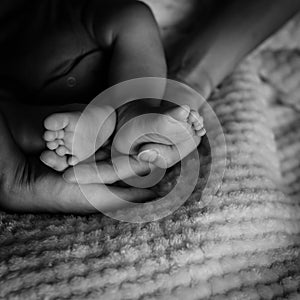 Filtered tone newborn Asian baby boy feet on mother hand palms
