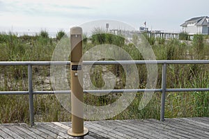 Filtered water bottle filler on a boardwalk neat a beach sand dune with high grass