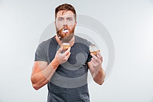 Filthy bearded young man eating cream cakes