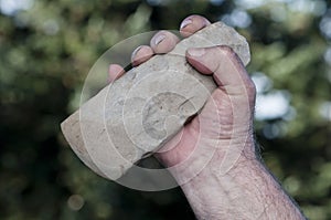 Filthy hand holding handaxe photo