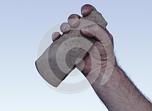 Filthy hand holding handaxe