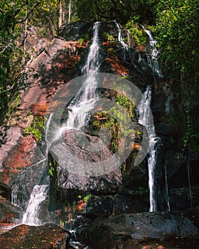 Filveda waterfall through green vegetation and red stones photo