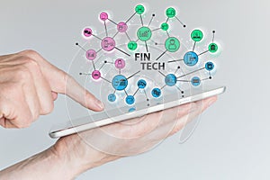 Fin Tech and mobile computing concept. Hand holding tablet with network of financial information technology objects