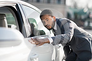 The final check. Afro man examining new car at dealership