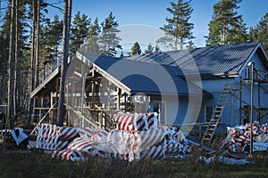 the final stage of construction of a large, gray, frame country house in a pine forest a