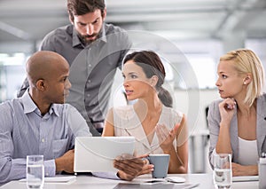 Finalising figures. a group of businesspeople discussing the contents of a tablet during a meeting.