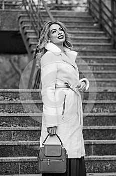 Finally here. girl warm coat stairs background. faux fur coat fashion. stylish business lady leather bag. glamour girl