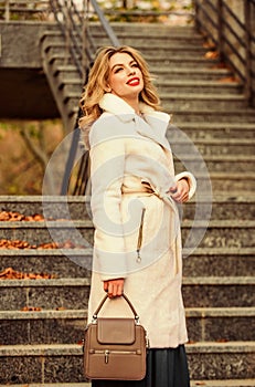 Finally here. girl warm coat stairs background. faux fur coat fashion. stylish business lady leather bag. glamour girl