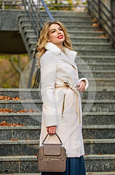 Finally here. girl warm coat stairs background. faux fur coat fashion. stylish business lady leather bag. glamour girl