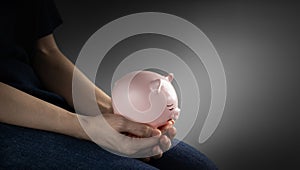 Finanacial crisis Concepts. a Depressed Person Holding a Sad Face Piggy Bank in the Gloomy Room. Mental Health Affected by