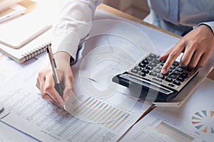 finance and accounting concept. business woman working on desk using calculator to calculate photo