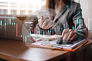 Finance accounting concept. Businesswoman working with smartphone and using a calculator to calculate the numbers of static in