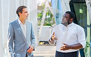 Finance, business and cooperation concept. Two successful businessmen are talking on the street. Office workers are