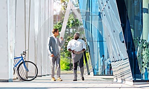 Finance, business and cooperation concept. Two successful businessmen are talking on the street. Office workers are