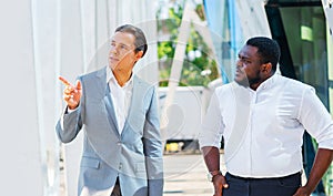 Finance, business and cooperation concept. Two successful businessmen are talking on the street. Office workers are