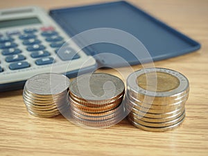 Finance business, pile of coins, money and calculator on wood background