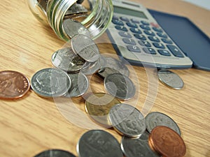 Finance, business, pile of coins, Thai money in glassware, calculator on wood background