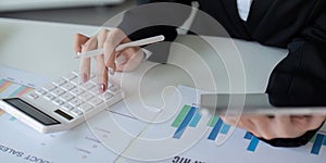 Finance concept. Close up businesswoman hold a graph pen and writing report, and memo, and analyzing business documents