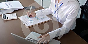 Finance concept. Close up businesswoman hold a graph pen and writing report, and memo, and analyzing business documents