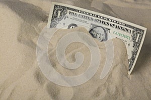 Finance concept. One dollar bank note in the sand