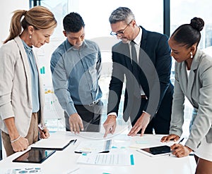 Finance, data and business people working on a graph in a modern office. Documents, teamwork and a multiracial group