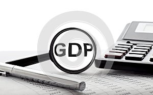 Finance and economics concept. Magnifier on a white background with text GDP, with pen,calculator and chart