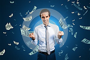 Finance freedom, money, wealth and success concept with powerful and happy man on blue background under dollar banknotes rain