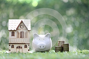 Finance, Model house with piggy bank and stack of coins money on natural green background,Business investment and real estate