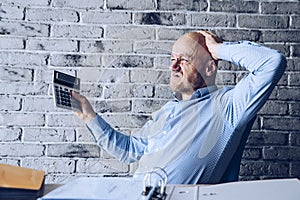 Finance problems and crisis. Worried manager in the office counting expences on calculator