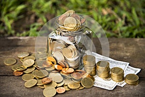 Save money with stack money coins put coin in glass jar and outside the glass jar on wooden  blurred green natural background mone