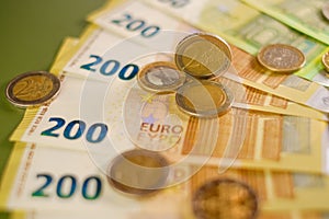 Finance and savings. euro coins and Two hundred euro banknotes on a dark green background.Expenses and incomes in
