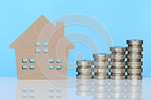 Finance, Stack of coins money and Model house on blue background, Saving money for prepare in future and real estate concept