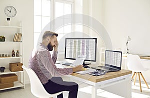 Financial accountant reading a document while doing paperwork at his office desk