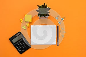 Financial or accounting background with place for text. A calculator, notebook, stationery on an orange background. conceptual