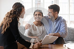 Financial advisor consulting diverse young family couple about deal.