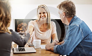 Financial advisor shaking hands with a female client after helping with budget, making a deal and planning with