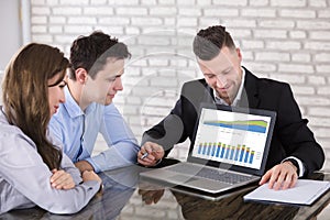 Financial Advisor Showing Graph On Laptop To Couple