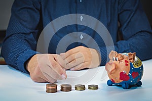 Financial advisor shows how much money you save on their services. A man puts the saved money into a piggy bank. Financial