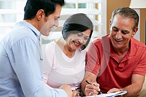 Financial Advisor Talking To Senior Couple At Home