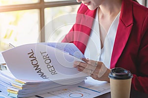 Financial, Asian businesswoman in red suit holding cup of coffee sitting on desk in office, having computer for doing accounting