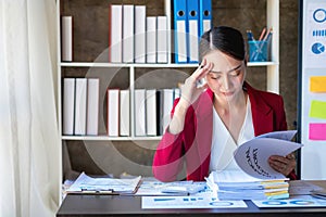 Financial, Asian businesswoman in red suit holding cup of coffee sitting on desk in office, having computer for doing accounting