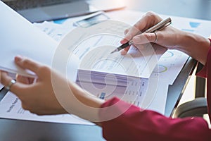 Financial, Asian businesswoman in red suit holding cup of coffee sitting on desk in office, having computer for doing accounting